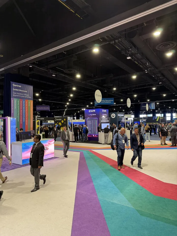 Attendees walking across the show floor past vendor booths