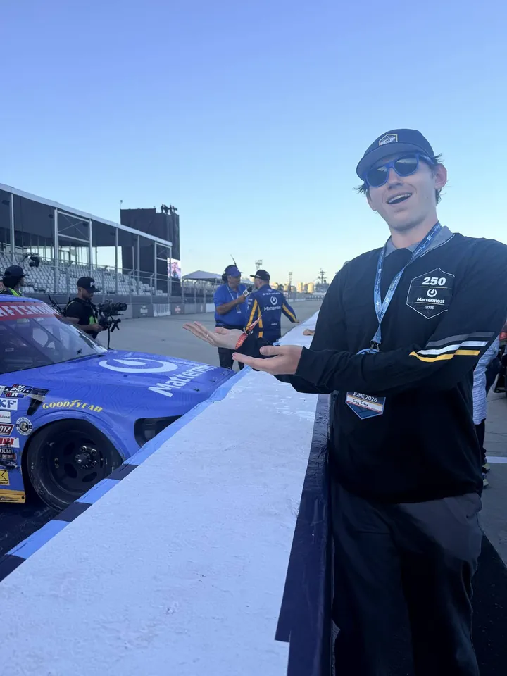 Greg in a Mattermost cap and sunglasses gesturing at the blue No. 34 truck on pit road after the win