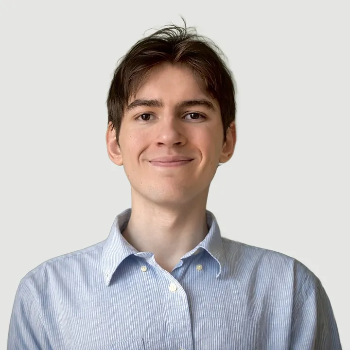 Greg Greco, smiling, in a light blue striped shirt