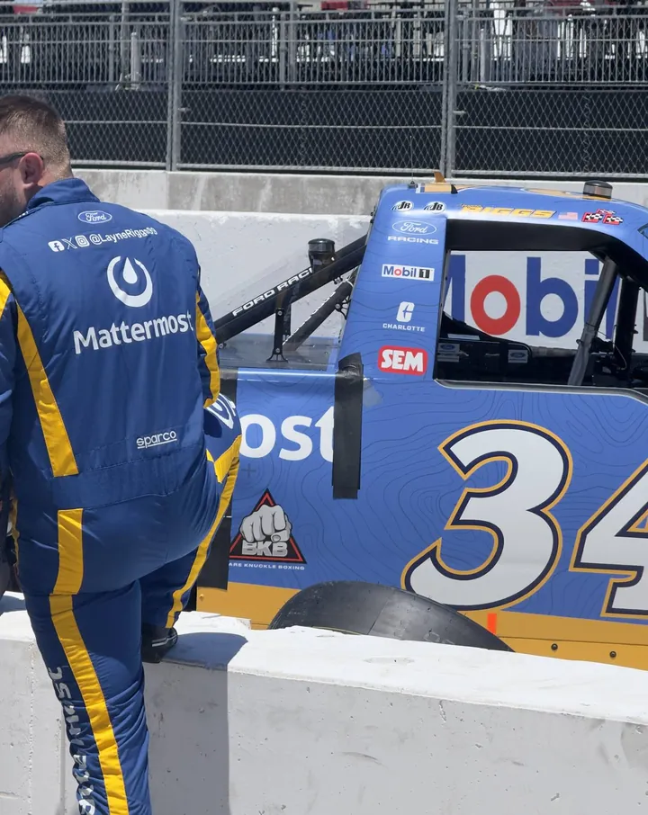A crew member in a blue Mattermost firesuit leans over the pit wall beside the No. 34 truck