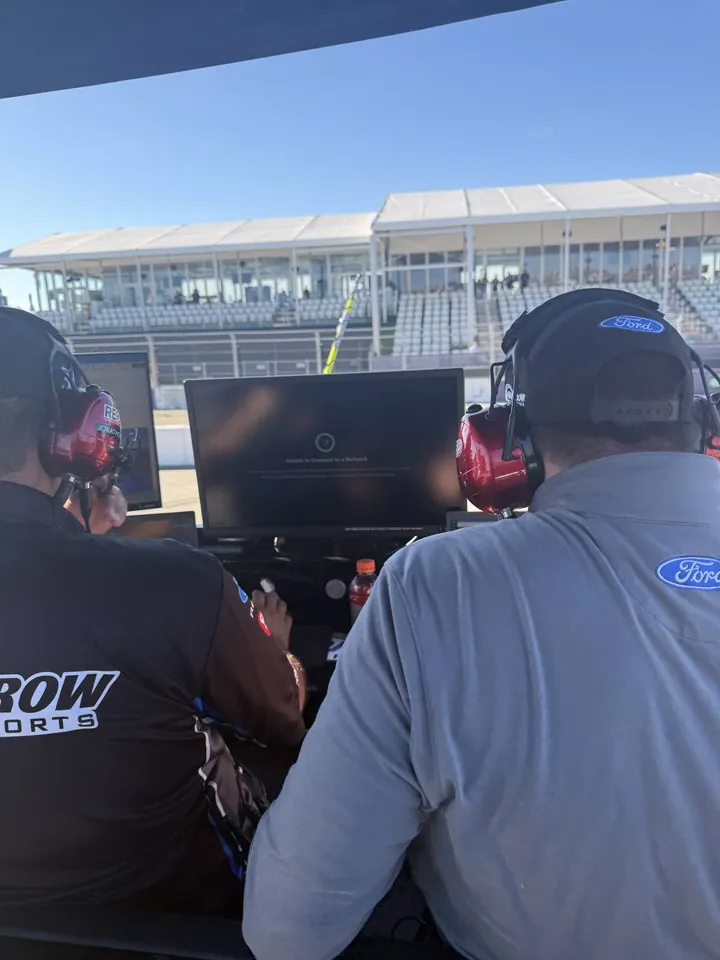 Crew members in headsets watching monitors on the pit box