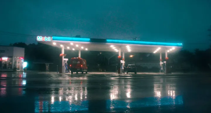 A Mobil gas station canopy glowing teal on a rainy evening