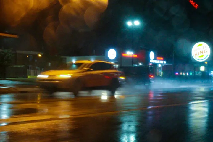 A yellow car blurred through rain at night