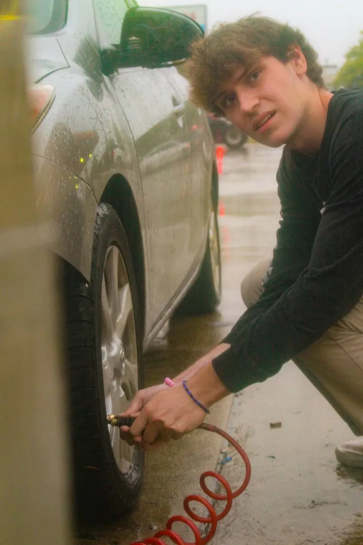 A friend filling a car tire with a red air hose